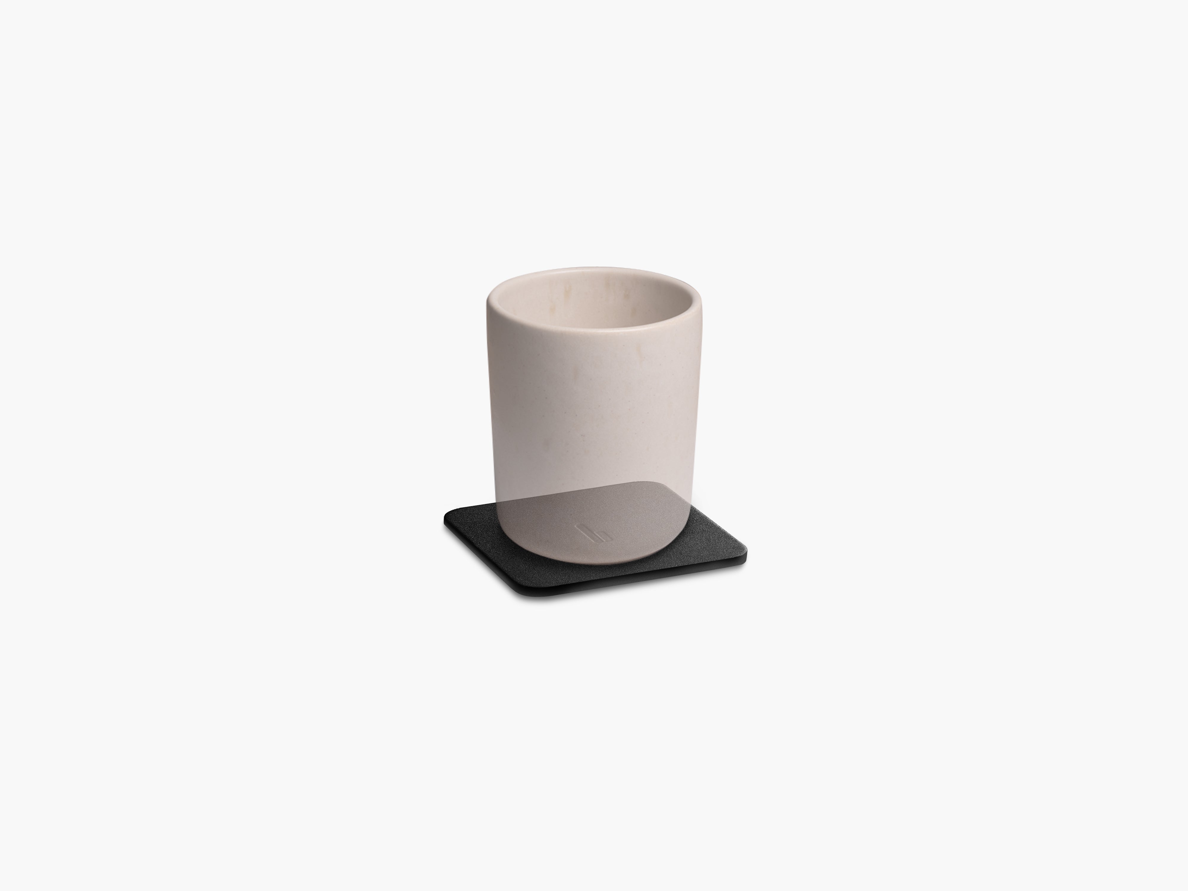 Produktfoto des Desk Coaster Leder, freigestellt auf grauem Hintergrund, veranschaulicht mit einer transparenten Tasse.