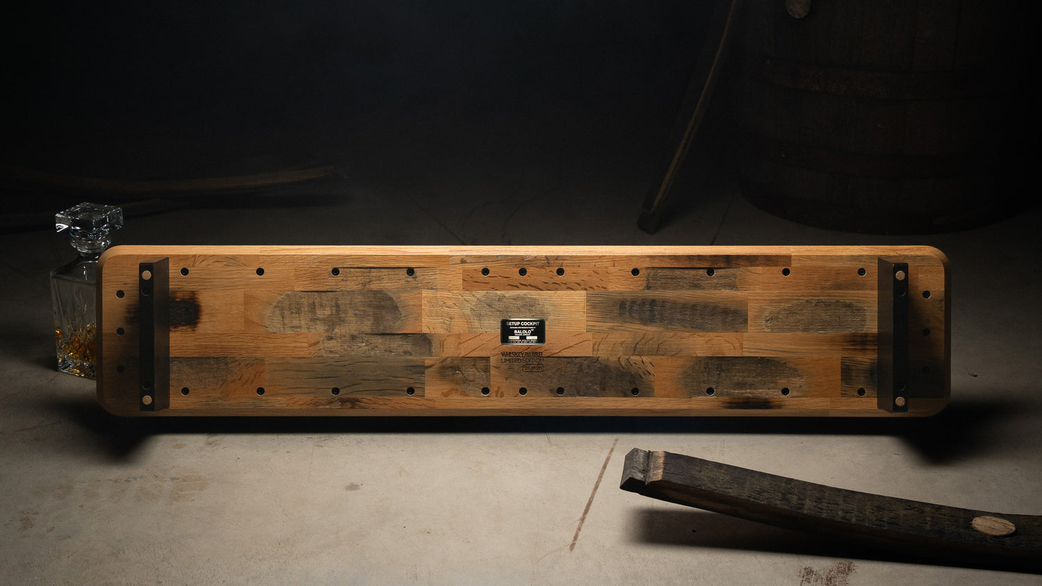 Hero Image der Whiskey Barrel Edition. Fokus liegt auf der Unterseite des Monitorständers in einer atmosphärischen Lagerhalle. In Szene gesetzt mit Eichenfass, Fassdauben und Karaffe.