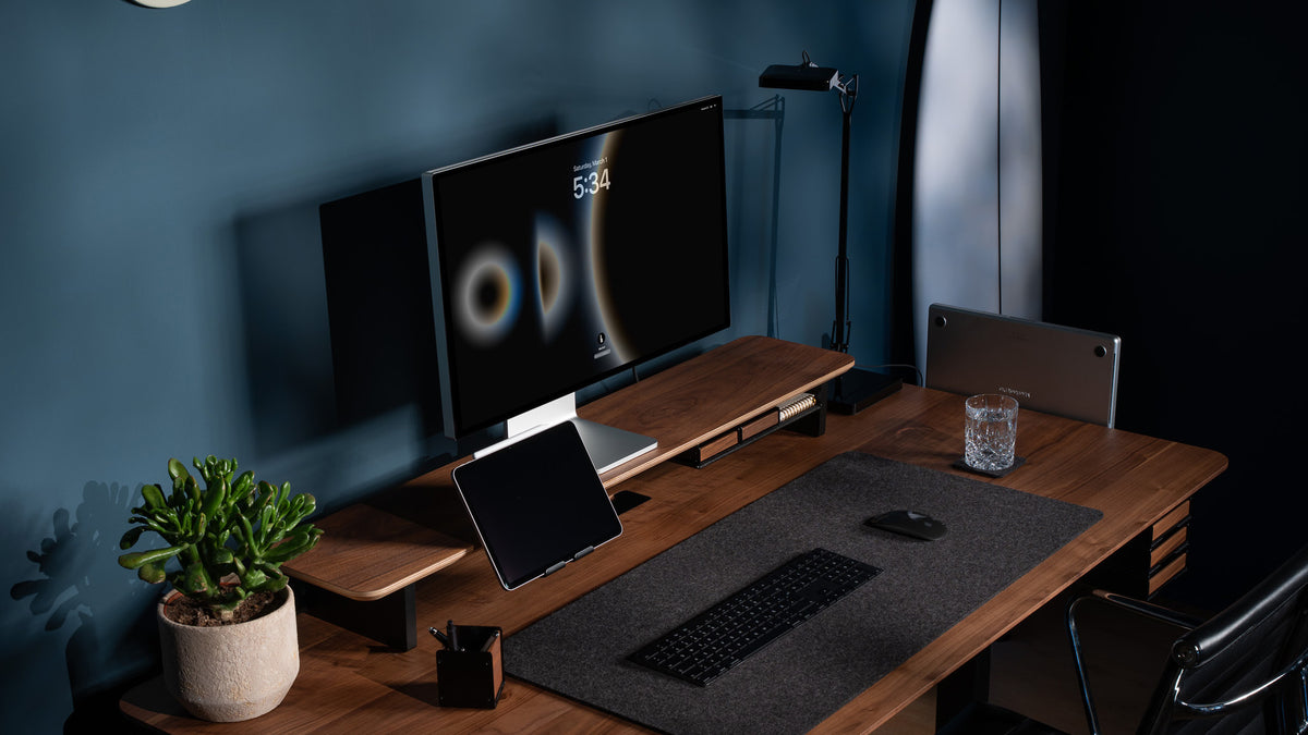 Walnuss-Schreibtisch vor dunkelblauer Wand mit Setup Cockpit, Tablethalter, Filz-Schreibtischunterlage, Stiftablage, Desk Coaster und Sukkulente