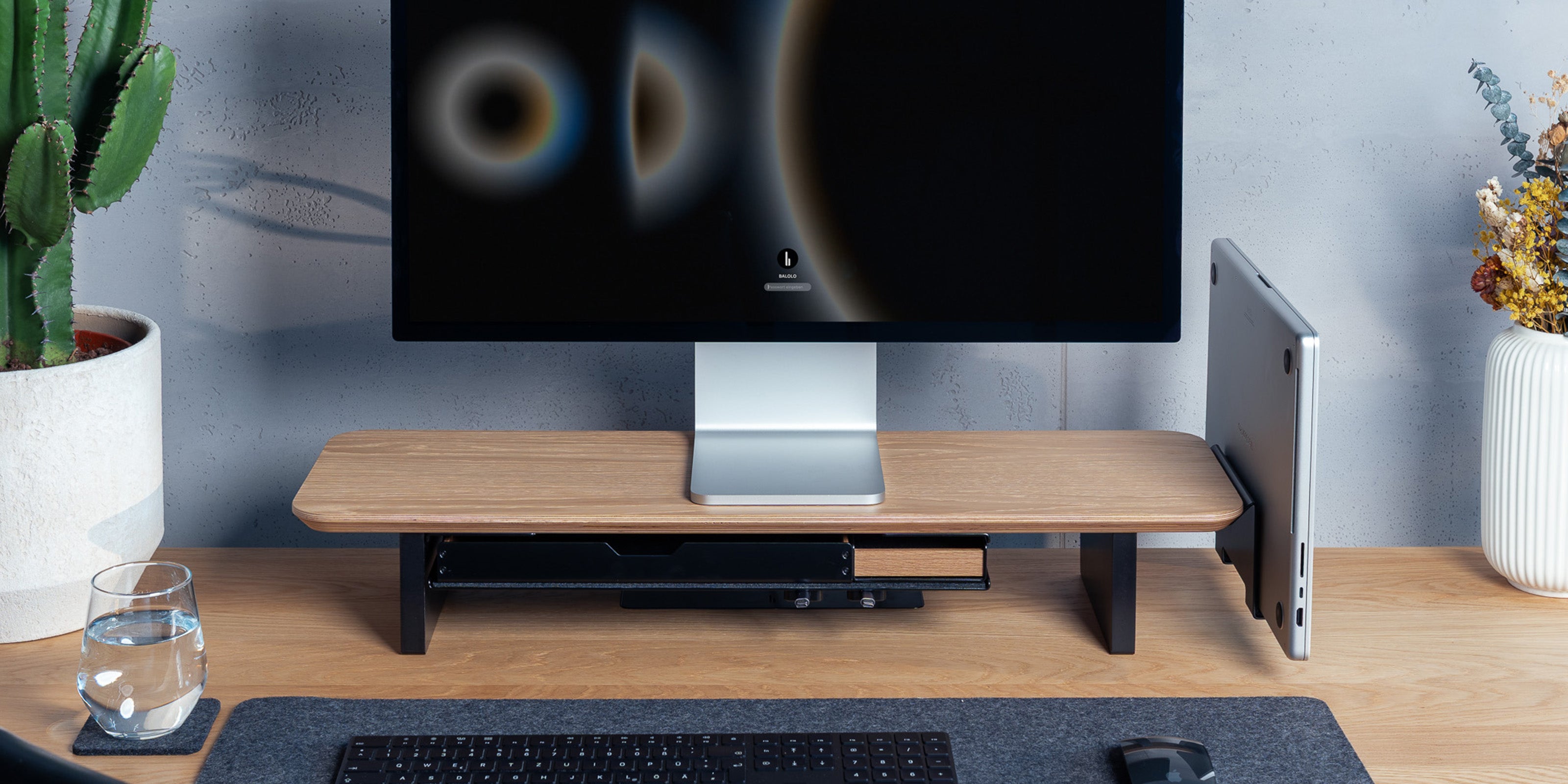 Setup Cockpit Monitorständer in Eiche auf einem Schreibtisch aus Eiche mit integriertem Laptophalter und Fach im modernen Office Setting.