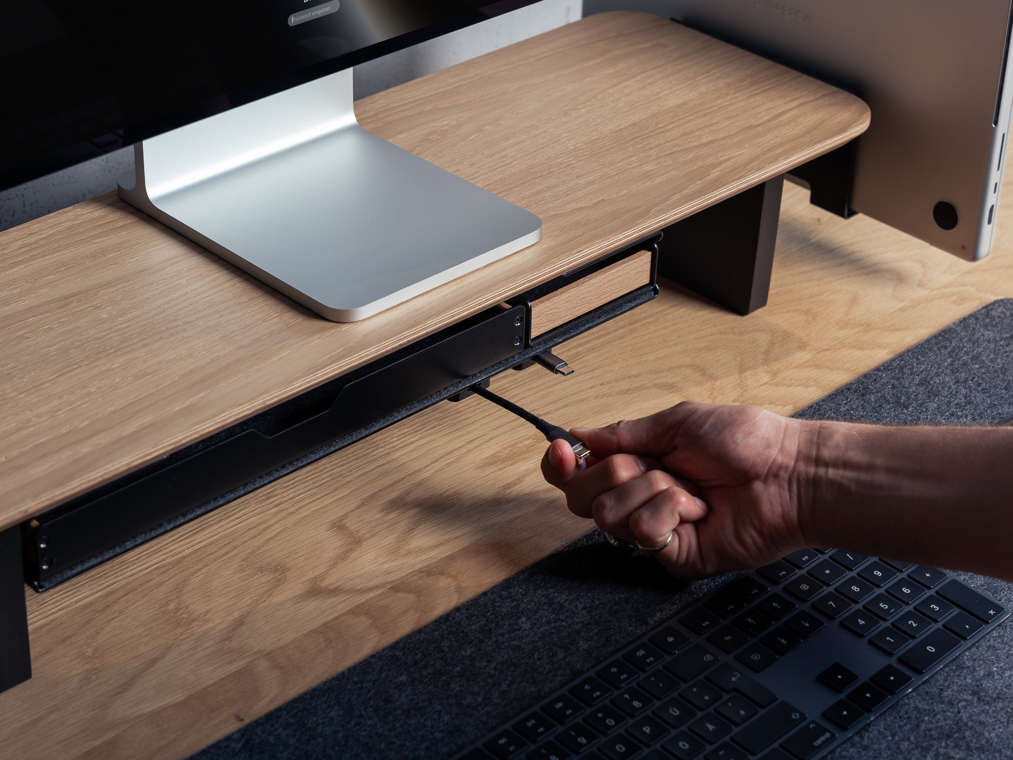 Detailansicht des großen Fachs unter dem Setup Cockpit aus Eiche. Fokus auf Kabelmagnet unter dem Fach, welches ein Ladekabel befestigt. @expand