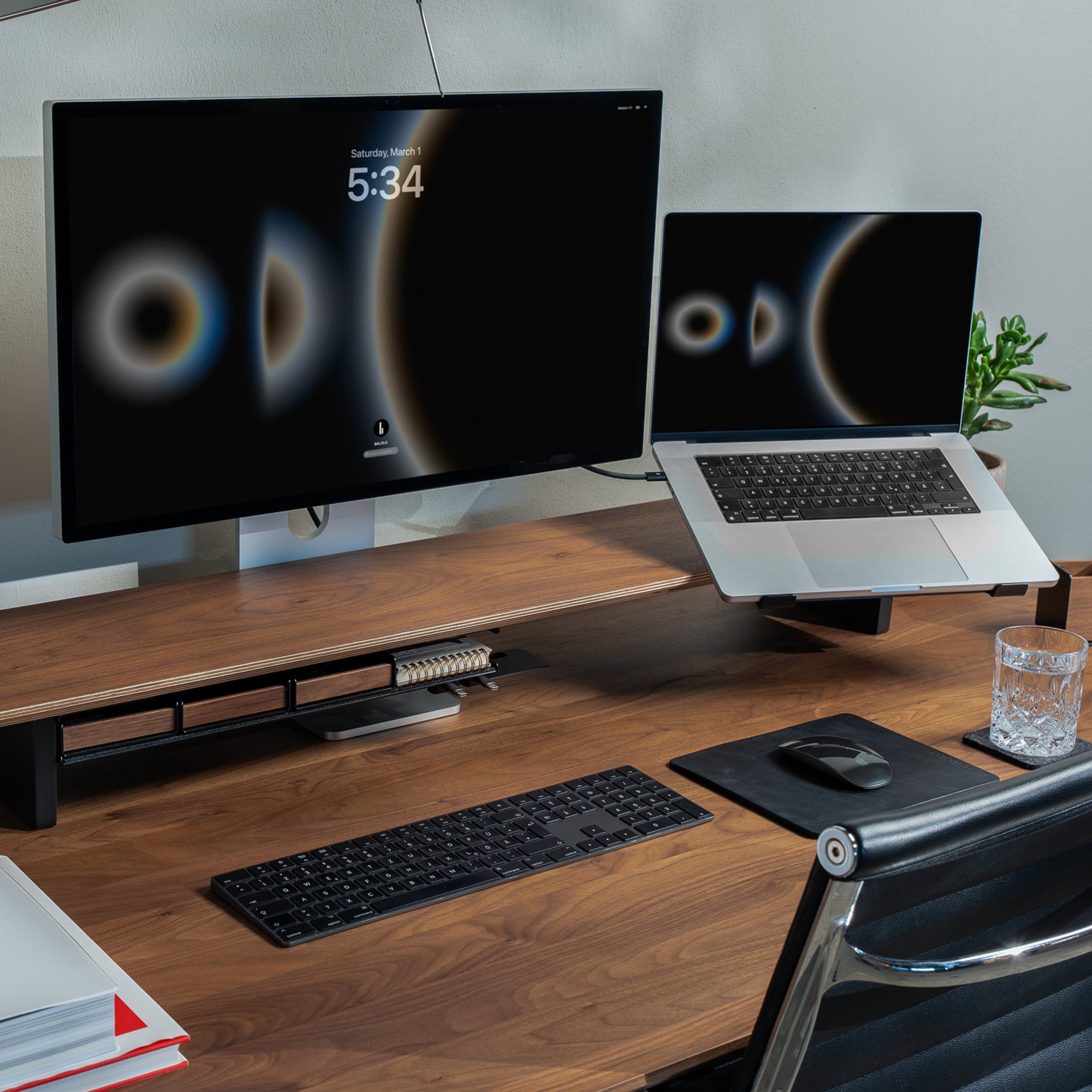 Setup Cockpit Monitorständer in Nussbaum auf einem Nussbaum Schreibtisch mit integriertem Laptophalter und Fach im modernen Office Setting.
