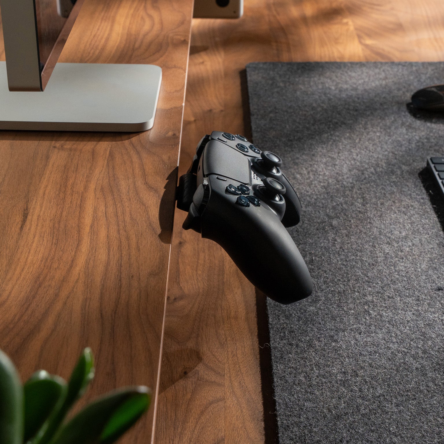 Detailaufnahme vom BALOLO Controller Halter mit PlayStation 5 Controller montiert am Setup Cockpit in Nussbaum in ästhetischen Schreibtischsetup. 