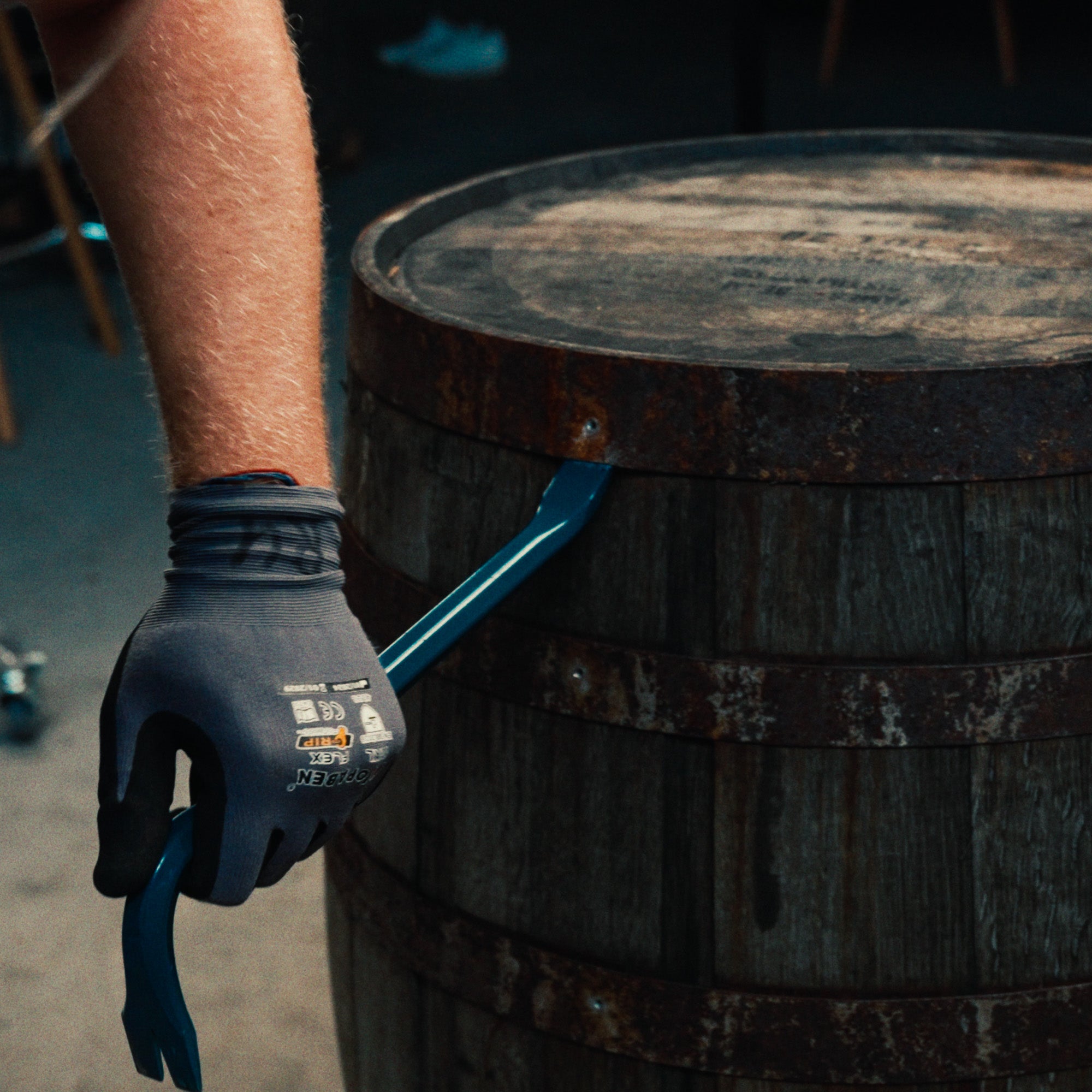 Detailaufnahme von Whiskeyfass, welches von Handwerker mit Werkzeug aufgehebelt wird.